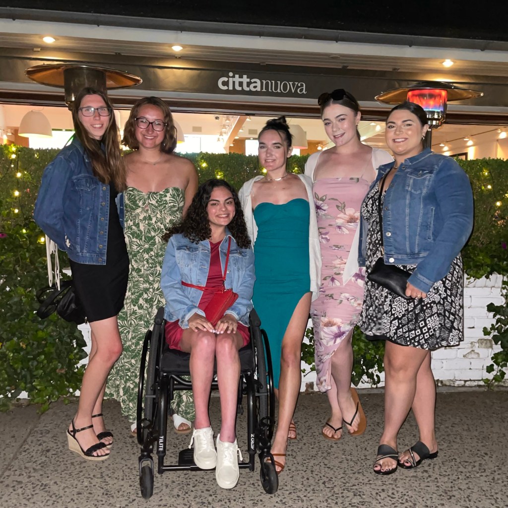 Five of my friends and I in front of a restaurant, wearing dresses.